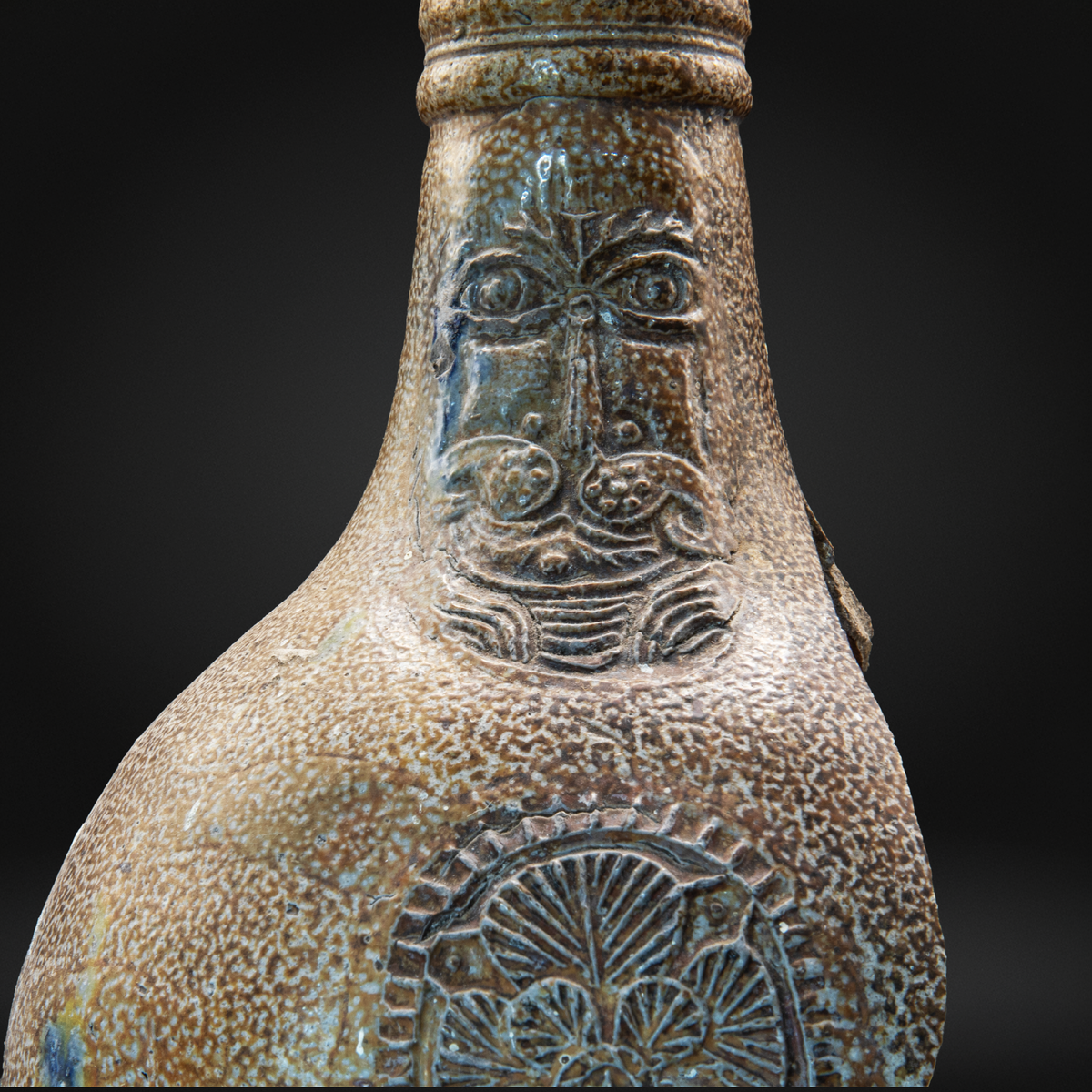 Close up view of a 16th or 17th century bellarmine witch bottle with a characterful face