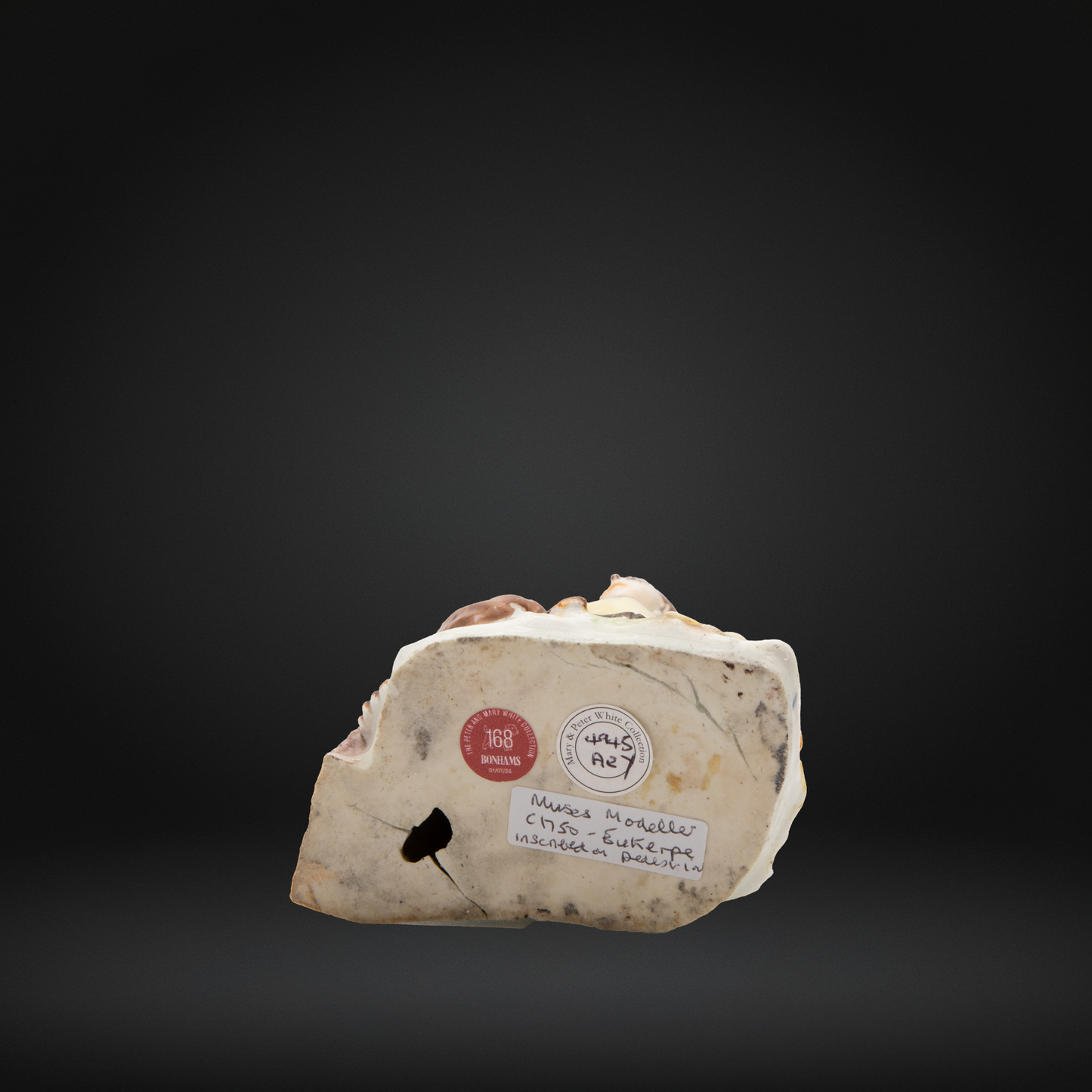 The base of an early Bow porcelain figure, featuring the collection stickers for the Peter and mary white collection and Bonhams.