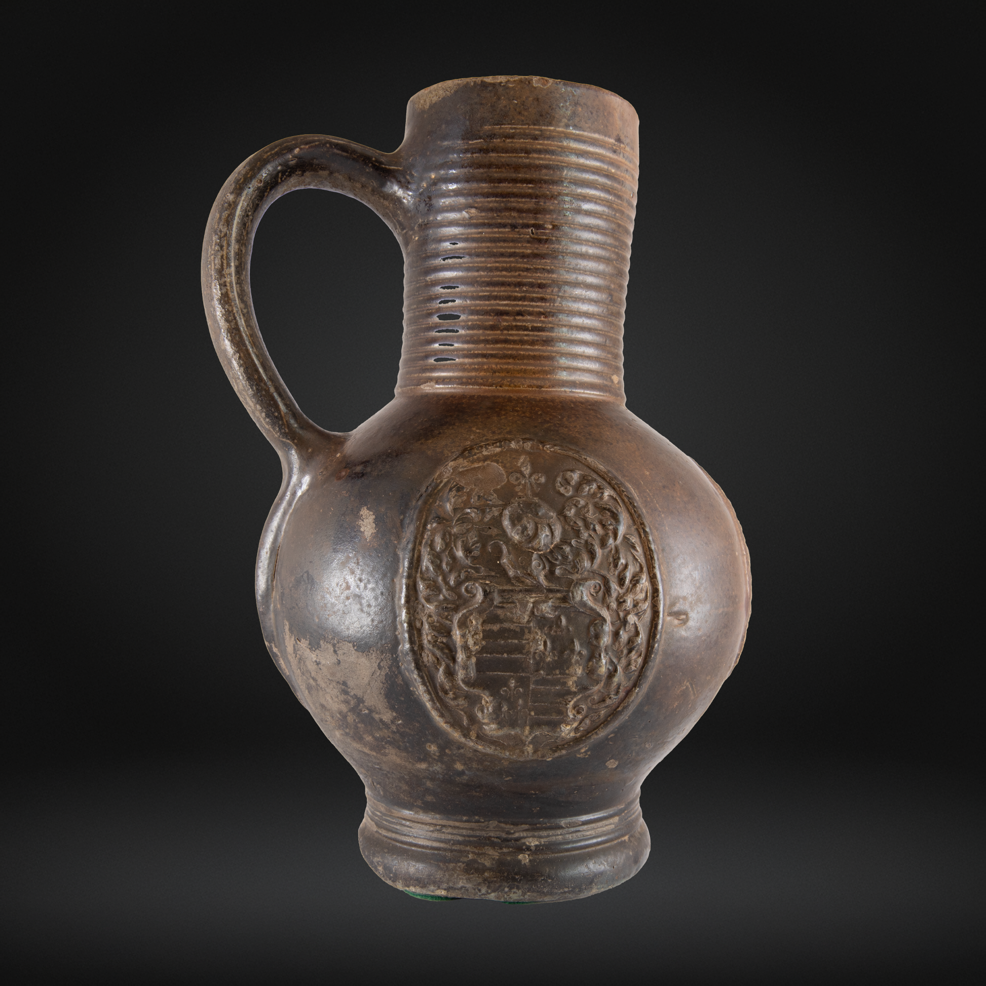 16th Century Raeren Stoneware Armorial Jug featuring detailed crest design on a rounded body with a ribbed neck and sturdy handle in antique German stoneware style.