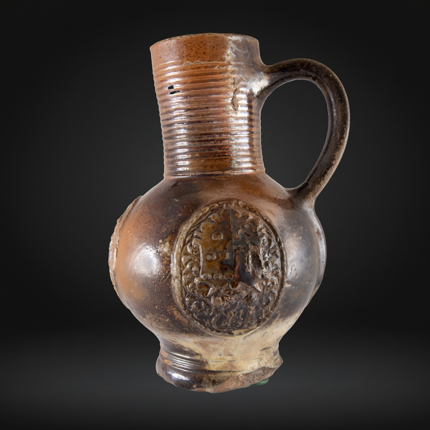 16th Century Raeren Stoneware Armorial Jug with a bulbous body, embossed crest detail, ribbed neck, and single curved handle in brown German stoneware.