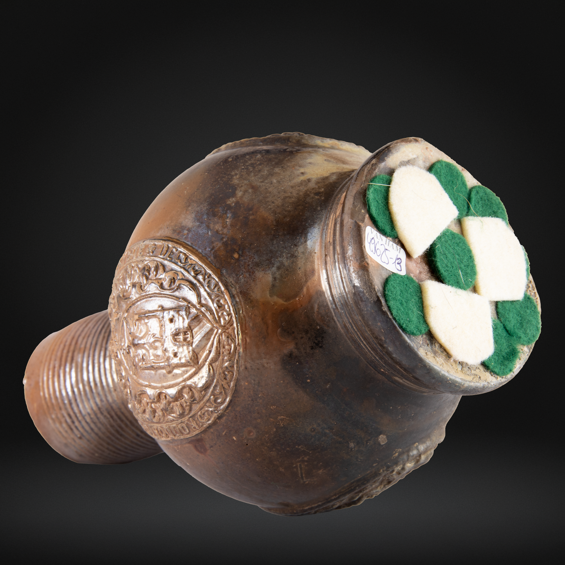 16th Century Raeren Stoneware Armorial Jug with detailed relieve decoration and a dark brown glazed surface, featuring green and white felt pads on the base.